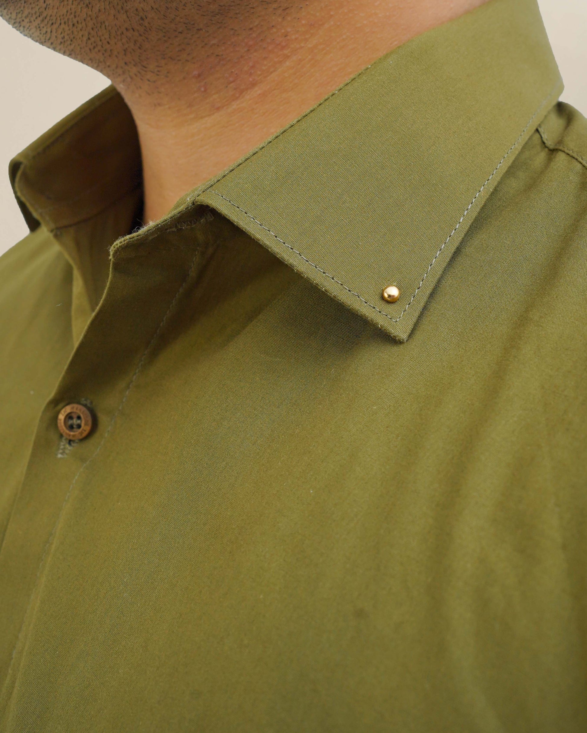 Close-up of a person wearing a green shirt with a collar detail.